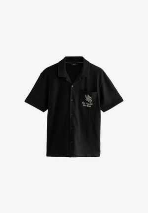 Must be shirt lühikeste varrukatega, pehmest kangast, millel on nupu ees, terav krae ja vasakul rinnal tasku, millel on kotka ja tekstiga kujundus.