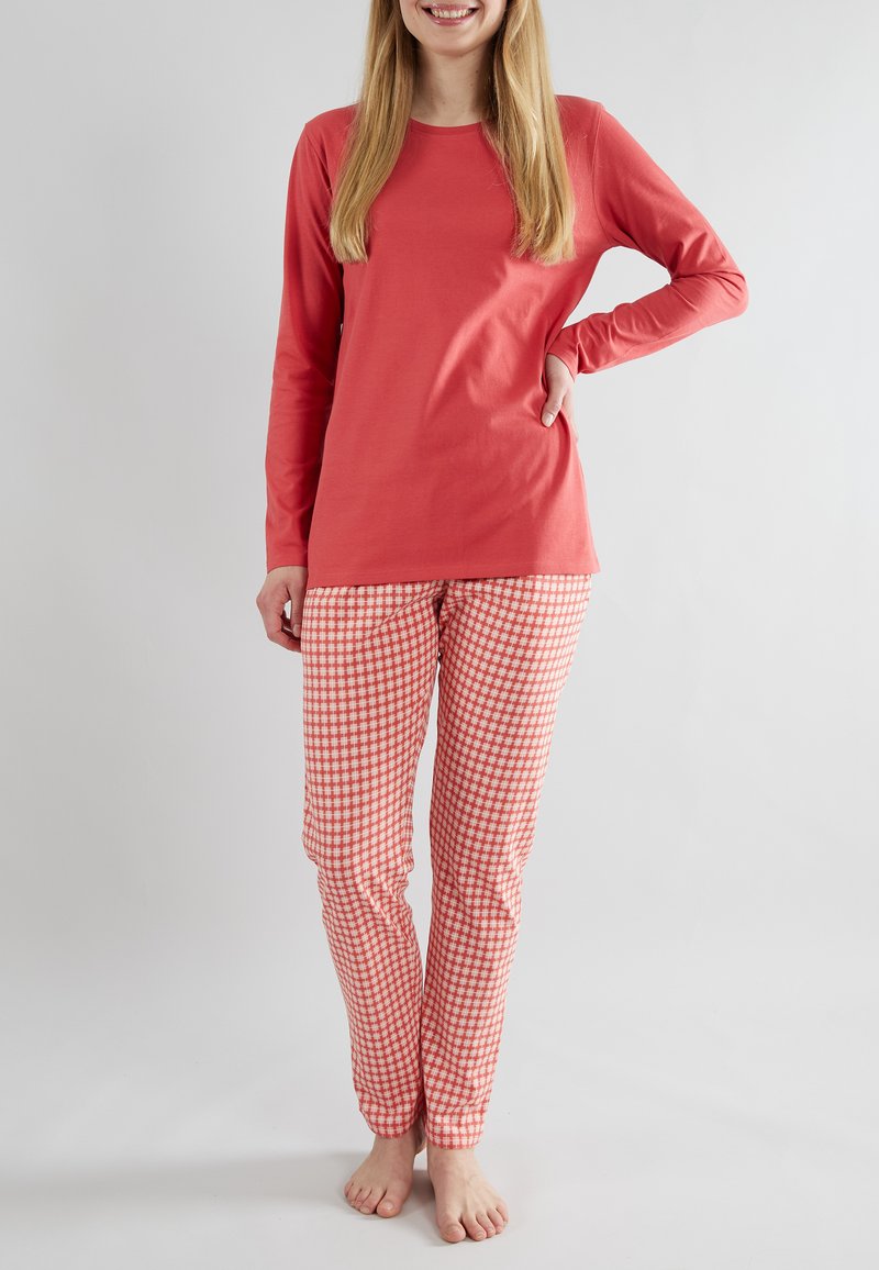 Haut corail à manches longues avec un col rond, associé à un pantalon de pyjama à carreaux rouges et blancs. Tissu en coton doux, coupe décontractée.