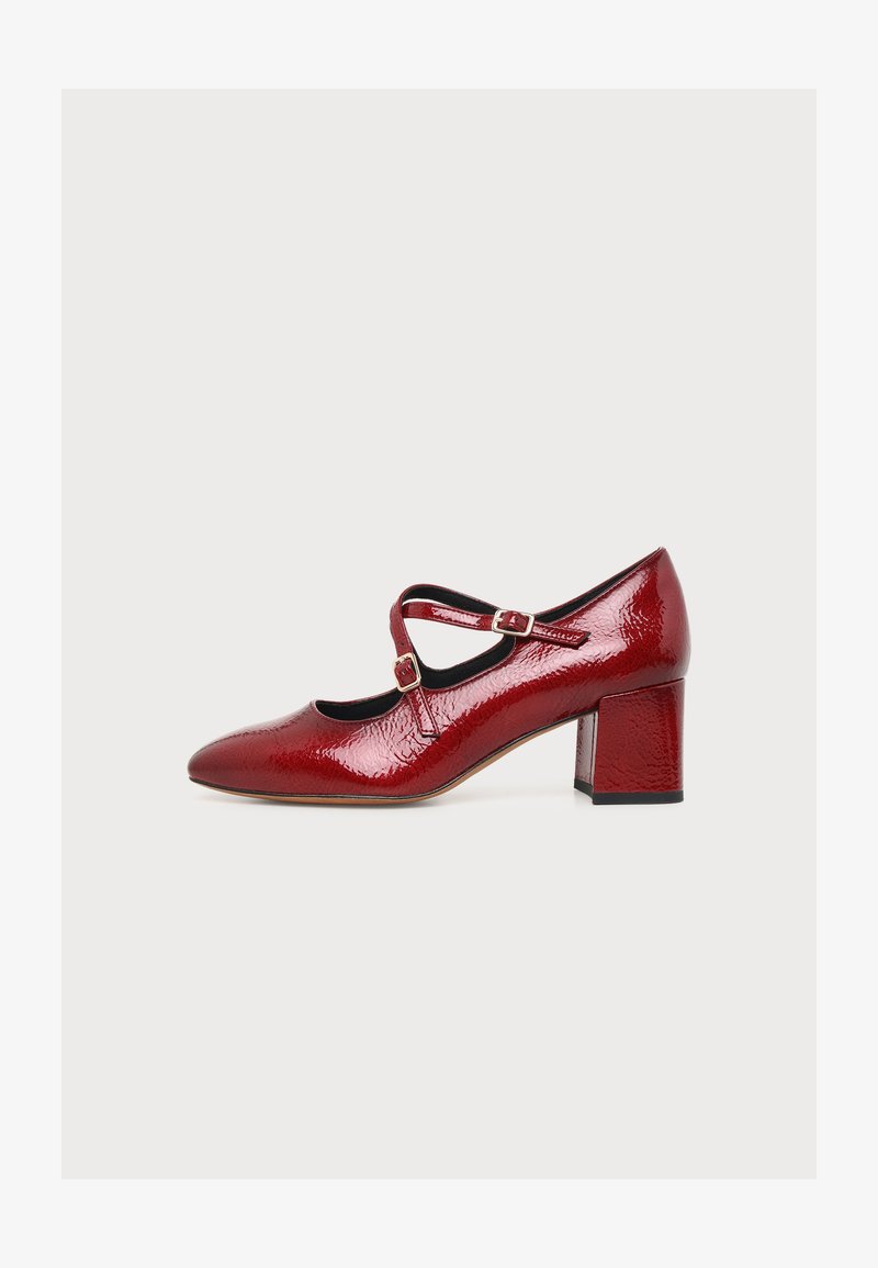 Chaussure Mary Jane en cuir verni rouge brillant avec deux brides à boucles et un talon bloc de hauteur moyenne sur fond blanc.