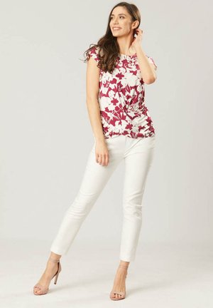 Bloemenprint top in wit en bordeauxrood met korte mouwen, gecombineerd met witte slim fit broeken en beige hakken.