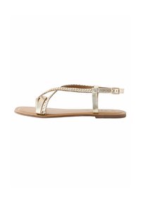 Gouden platte sandalen met gevlochten bandjes, een ronde neus en een verstelbare enkelband op een soepele bruine zool.