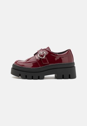 Glänzende bordeauxfarbene Lacklederschuhe mit einer klobigen schwarzen Sohle und Herzförmigem Schnallenakzent. Klassisches Schnürdesign mit runder Zehenform.