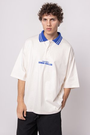 Off-white polo shirt with a blue striped collar, featuring a front graphic that reads "BURNING REBELLION" in bold blue letters.