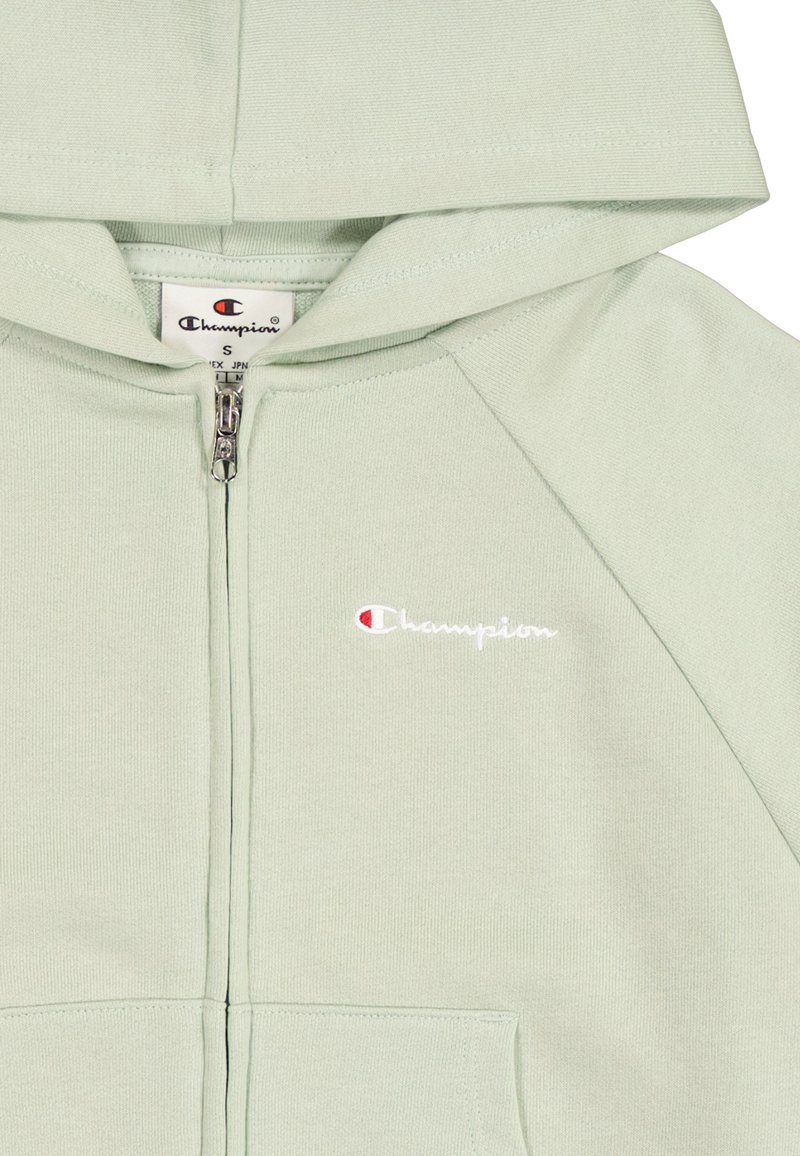 Jasnozielona bluza z kapturem na zamek błyskawiczny o luźnym kroju, wyposażona w kaptur, ściągacze u rękawów oraz małe haftowane logo w kolorze białym i czerwonym po lewej stronie klatki piersiowej.
