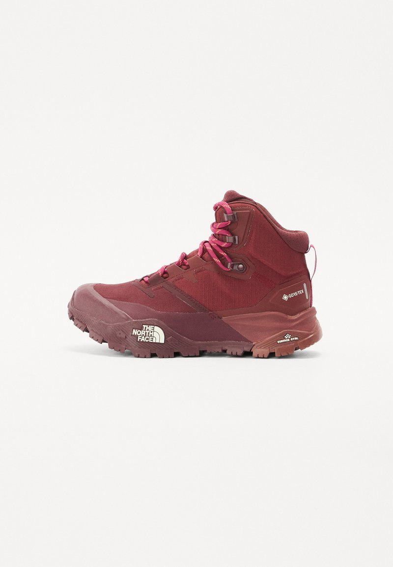 Botas de caminhada vermelhas com um cabedal em tecido texturizado, biqueira reforçada e sola de borracha. Apresentam atacadores cor-de-rosa e um logotipo na lateral.