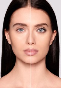 Metà del viso con tono di pelle naturale e texture liscia; un lato presenta ciglia definite e trucco sottile, l'altro è nudo con labbra lucide.