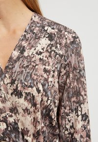 Lätt blus med omslag, i lättviktig tyg och med ett flerfärgat, abstrakt mönster i nyanser av mauve, krämfärgad och svart; djup V-ringning.