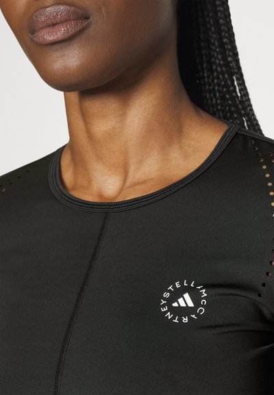 Black athletic top with mesh detailing; features short sleeves and a round neckline; white logo accent on left chest area.