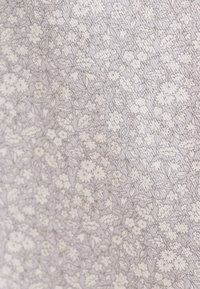 Tessuto leggero con un delicato motivo floreale in morbido grigio e bianco, caratterizzato da piccoli fiori e foglie, che offre un aspetto texture.