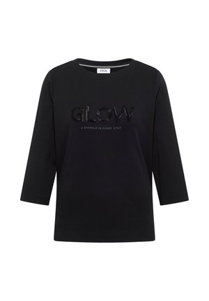 Czarna koszulka z trzymi półrękawami, uszyta z miękkiej bawełny, z napisem "GLOW" wysadzanym czarnymi kryształkami oraz tekstem "& SPARKLE IN EVERY STEP" poniżej.