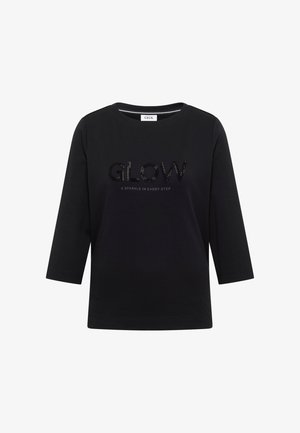 Schwarzes T-Shirt mit drei Viertelärmeln aus weicher Baumwolle, das das Wort "GLOW" in schwarzen Strasssteinen zeigt, mit dem Text "& SPARKLE IN EVERY STEP" darunter.