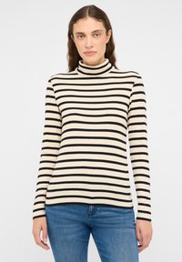 Haut à col roulé rayé crème et noir, avec manches longues et texture côtelée, associé à un jean bleu.