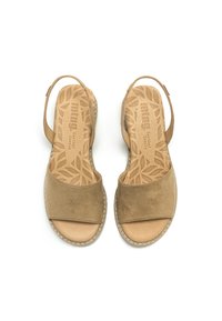 Sandales beiges avec une tige en daim et une semelle intérieure rembourrée présentant un motif de feuille. Sangle réglable au talon avec une semelle texturée.