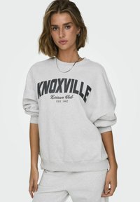Felpa grigia con la scritta "KNOXVILLE Leisure Club EST. 1982" stampata in nero. Presenta polsini e orlo a coste, vestibilità comoda e una texture morbida.