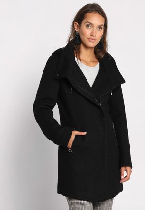 Black wool blend coat with a large collar, asymmetrical zipper, and two side pockets. Textured fabric and sleek design.