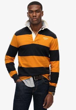 Lange mouw polo in oranje en marineblauwe strepen, met een witte kraag, geborduurd logo en denim jeans. Getextureerde katoenstof.