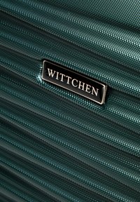 Valise vert foncé avec des rayures verticales texturées. Plaque logo WITTCHEN noire bien visible fixée. Matériau synthétique durable renforçant la durabilité.