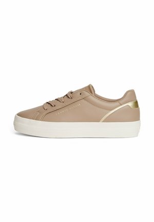 Sneakers sintetici beige con una finitura liscia, suola in gomma bianca e dettaglio dorato sul retro. Presentano sei asole e punta rotonda.