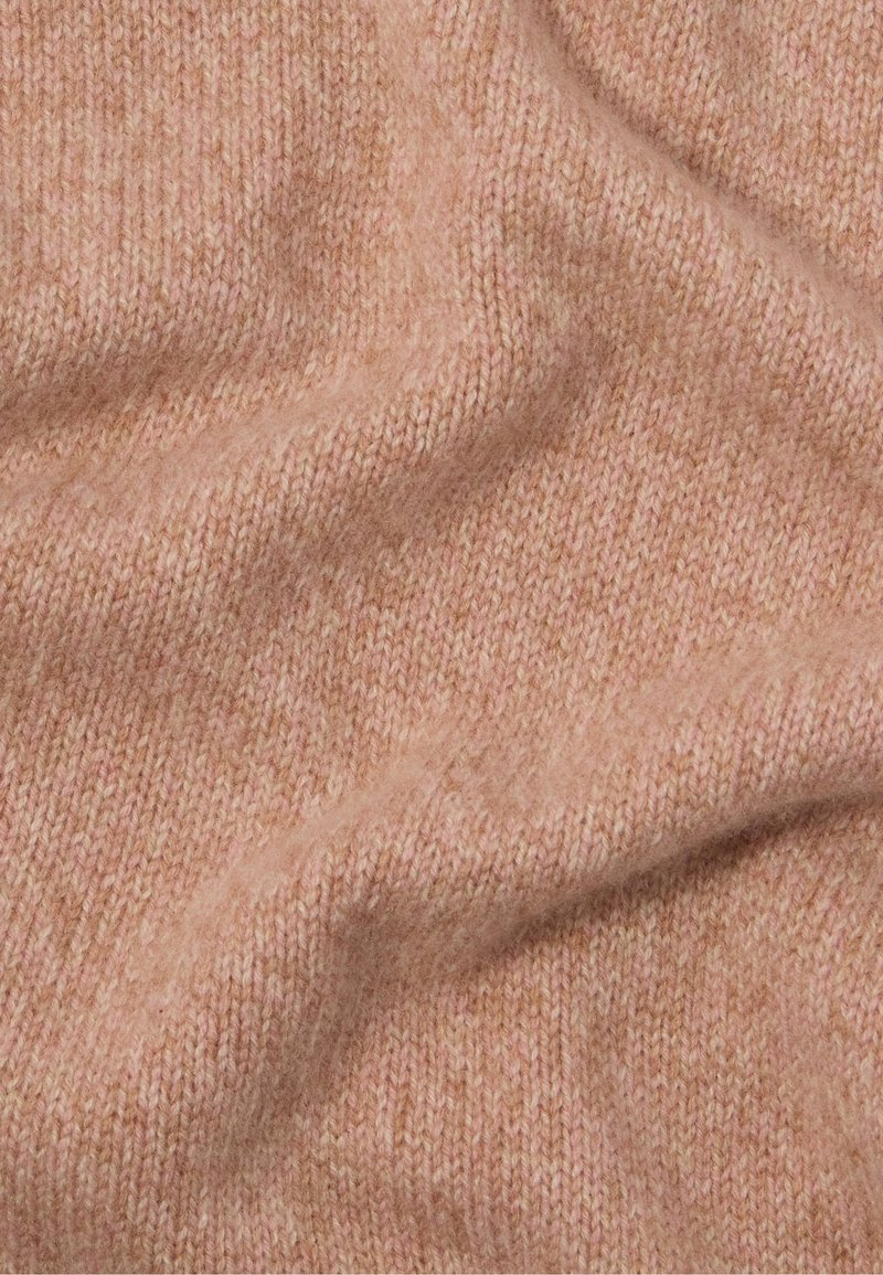 Gebreide stof in zacht roze met een fijne ribbelstructuur, waarin subtiele kleurvariaties en een delicate, warme uitstraling te zien zijn.