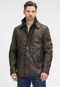 Braune Lederjacke mit Knopfverschluss, zwei Fronttaschen, einer gefütterten Innenschicht mit Reißverschluss und einem hohen Kragen, die eine glatte, strukturierte Oberfläche präsentiert.