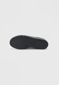 Talpa de pantof de cauciuc negru cu un model texturat în grilaj și logo-ul "CK". Formă curbată și margini netede pentru un design aerodinamic.