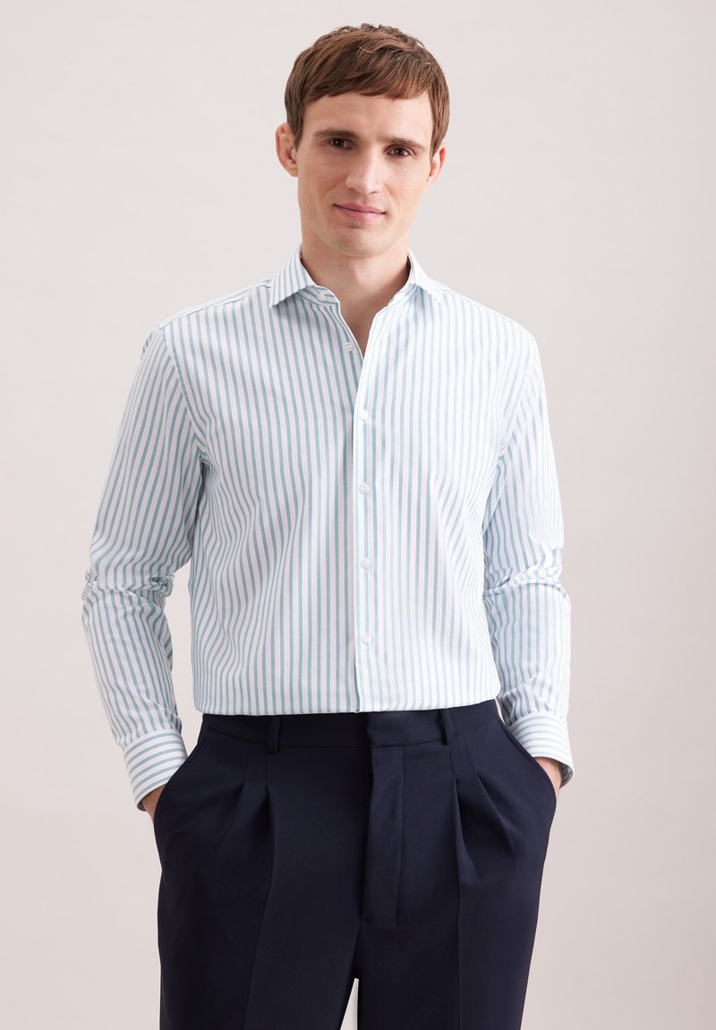 Hemd mit durchgehender Knopfleiste in hellblau-weiß gestreift, aus leichtem Stoff, mit Haifischkragen und langen Ärmeln, in dunkle Hosen gesteckt.