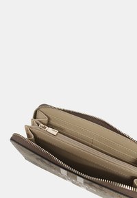 Portefeuille beige avec un extérieur texturé, plusieurs emplacements pour cartes, un compartiment zippé et une tirette en argent. Contient un intérieur lisse.