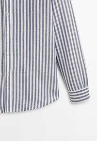 Chemise à manches longues avec des rayures verticales bleu marine et blanches, des boutons blancs sur le devant, et un poignet avec des rayures horizontales sur fond blanc.