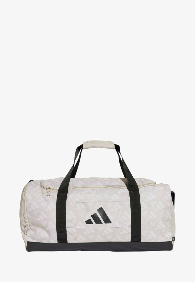 Il borsone presenta un tessuto beige chiaro con un motivo geometrico, accenti neri, manici robusti e un compartimento principale con zip.