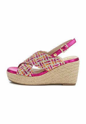 Sandalia de cuña con una correa trenzada multicolor y acentos metálicos en rosa. Presenta una suela envuelta en yute y una correa ajustable en el tobillo.
