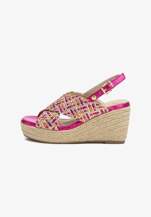Sandalia de cuña con una correa trenzada multicolor y acentos metálicos en rosa. Presenta una suela envuelta en yute y una correa ajustable en el tobillo.