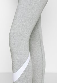Leggings sportivi grigi realizzati in un morbido tessuto testurizzato, con una striscia di accento bianco lungo il lato e un design aderente.