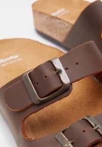 Smeđe kožne sandale s podlogom od pluta, s podesivim trakama i metalnim kopčama. Površina ima glatku teksturu s prirodnim završetkom.