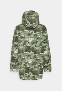 Álcázott mintázatú kapucnis dzseki különböző zöld árnyalatokban, sima felülettel és egyenes szabással, cipzáras zárással.