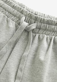 Light gray sweatpants with an elastic waistband and drawstring. Soft texture with gathered stitching along the waistband.