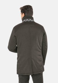 Cappotto grigio scuro con colletto alto, con fodera a quadri. Texture liscia, design imbottito, tasche laterali e dettagli sulla cucitura posteriore.