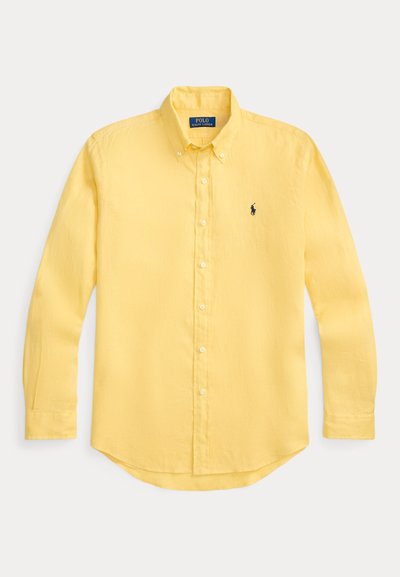 Κίτρινο πουκάμισο με μακριά μανίκια και κουμπιά, ελαφρύ ύφασμα, μυτερός γιακάς, στρογγυλεμένο τελείωμα, με μικρό κεντημένο λογότυπο στο αριστερό στήθος.
