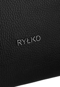 Fekete bőr táska, textúrált felülettel. Az elülső részen ezüst fémes "RYŁKO" logó van debosszolva, ami figyelemre méltó részletet ad.