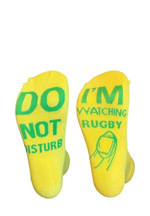 Gele sokken met groene tekst die "STOOR NIET" en "IK KIJK RUGBY" zeggen, voorzien van een afbeelding van een rugbyspeler. Zacht, rekbaar breimateriaal.