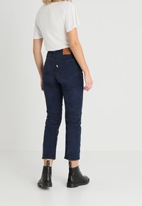 Navyblå högmidjade jeans med en figursydd silhuett och ankellängd, med en läderlapp på den bakre midjebandet och subtil textur.