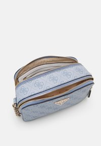 Modrá textilní kabelka přes rameno s texturovaným povrchem, dvojicí zipových přihrádek a kovovým logem. Podšívka z béžové látky.