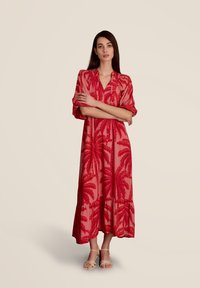 Robe maxi rouge avec des manches courtes et un décolleté en V, ornée d'un motif de feuilles de palmier et d'un ourlet à volants. Fabriquée en tissu léger pour un confort optimal.