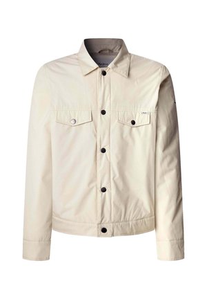 Giacca beige realizzata in tessuto leggero, con chiusura a bottoni sul davanti, due tasche sul petto e colletto. Bottoni neri offrono un contrasto.