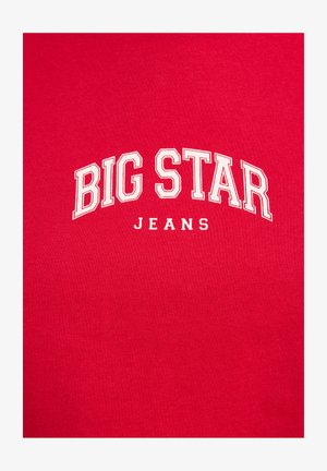 Punane puuvillane T-särk ribakujulise tekstuuriga, millel on valged plokktähed sõnadega "BIG STAR" üleval ja "JEANS" kõveras paigutuses.