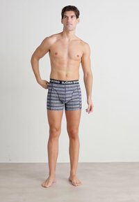 Moške boksarice z črnimi pasom, na katerem je napis "BJÖRN BORG." Oblikovane z modrimi in belimi geometrijskimi vzorci, raztegljiv material.