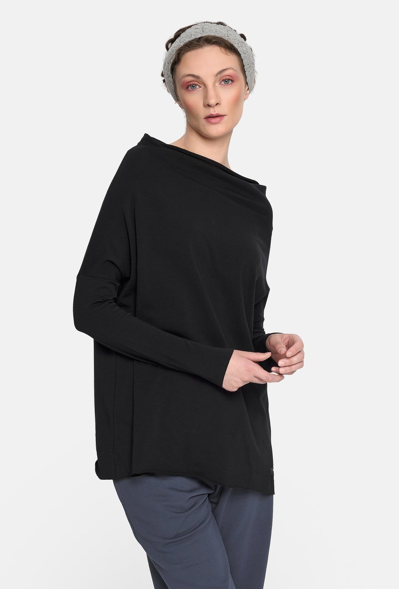 Czarny długi rękaw top z luźnym krojem, miękkim materiałem, asymetrycznym dekoltem i bocznymi rozcięciami, w połączeniu z luźnymi szarymi spodniami.