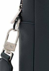 Dunkelblaue Lederhandtasche mit strukturiertem Oberflächen, silbernem Zubehör und einem Reißverschluss-Zipper mit einem Markenetikett. Verstellbarer Trageriemen ist enthalten.