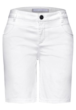 Close-up van een persoon die witte broek draagt met achterzak en een blauw-wit gestreept overhemd dat is ingestopt.