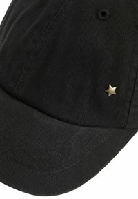 Casquette en velours côtelé noir avec une couronne arrondie et une visière courbée, comportant une petite embellissement en étoile dorée sur le côté.