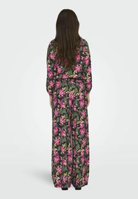 Blommig jumpsuit i mörkgrön med rosa och krämfärgade blommor, långa ärmar och vid ben-design. Lättviktsmaterial; subtile struktur.